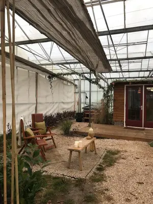 a greenhouse with chairs and a table in a yard at Unique Tiny House close to Ams Airport with Hottub in Rijsenhout
