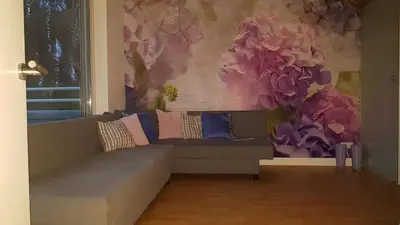 a living room with a couch and flowers on the wall at Lil Amsterdam Topfloor a room ensuite with balcony in Uithoorn