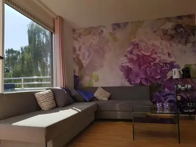 a living room with a couch and a flower mural at Lil Amsterdam Topfloor a room ensuite with balcony in Uithoorn