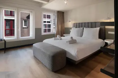 a bedroom with a large white bed and two windows at Hotel Zeedijk City Centre in Amsterdam