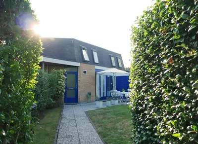 a house with blue doors and a table and chairs at Gemütliches Ferienhaus am Meer in Ons Belang