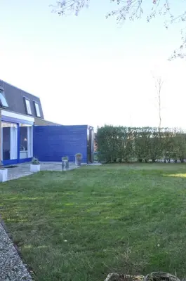 a yard with a blue house with a dog at Gemütliches Ferienhaus am Meer in Ons Belang