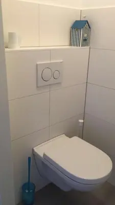 a bathroom with a white toilet and a toilet brush at Gemütliches Ferienhaus am Meer in Ons Belang