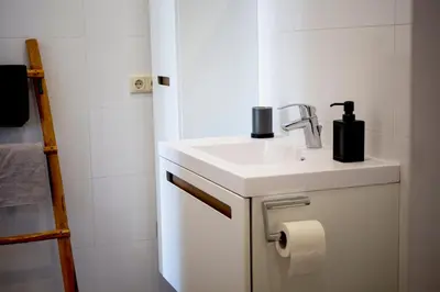 a white bathroom with a sink and a towel at Vorstelijk verblijf Alkmaar in Alkmaar