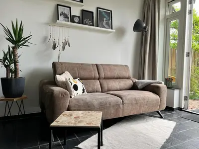 a brown couch in a living room with a table at Vorstelijk verblijf Alkmaar in Alkmaar