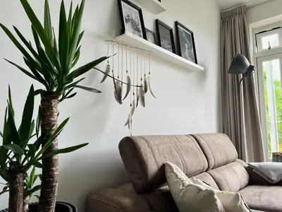 a living room with a couch and a palm tree at Vorstelijk verblijf Alkmaar in Alkmaar