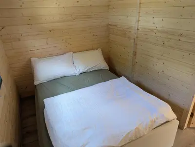 a small bedroom with a bed in a wooden room at The Bee - Trekkershuts & Apartment in Opperdoes