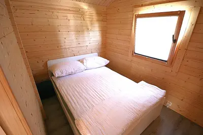 a small room with a bed in a wooden cabin at The Bee - Trekkershuts & Apartment in Opperdoes
