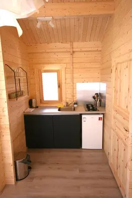 a kitchen in a wooden cabin with a sink and a refrigerator at The Bee - Trekkershuts & Apartment in Opperdoes