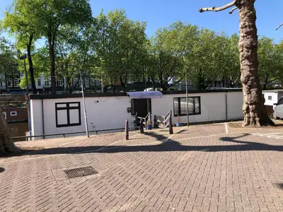 a white building with a tree in a park at Amsterdam-Houseboat-Amstel in Amsterdam