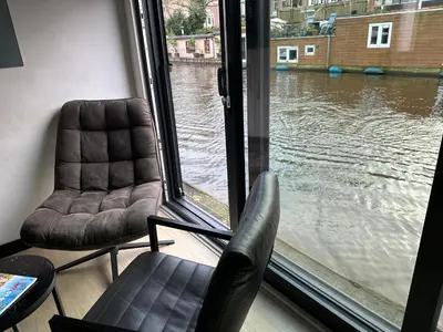 two chairs in front of a window with a view of water at Amsterdam-Houseboat-Amstel in Amsterdam