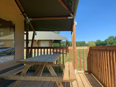a picnic table on the deck of a house at Trio Lodge in Zeewolde
