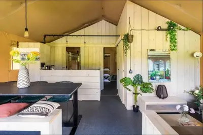 a kitchen with yellow walls and a table and benches at Trio Lodge in Zeewolde