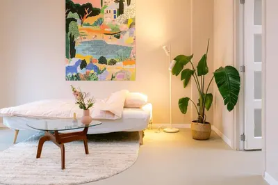 a living room with a bed and a table at Nice bright studio near the forest and Amsterdam in Baarn