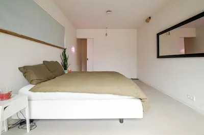 a white bedroom with a bed and a mirror at La Casa Goudacito in Gouda