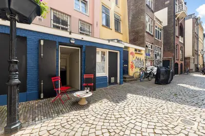 a building with red chairs and a table on a street at Unique underground hotel in Utrecht city center in Utrecht