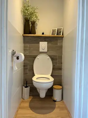 a bathroom with a toilet with a wooden wall at BeachHouse ibiza 19A in Noordwijk aan Zee