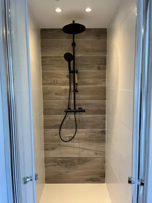 a shower in a bathroom with a wooden wall at BeachHouse ibiza 19A in Noordwijk aan Zee