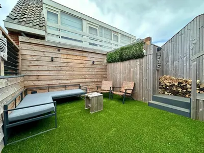 a backyard with a bench and a fence at Catwijck Loft in Katwijk aan Zee