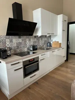 a white kitchen with white cabinets and a sink at Catwijck Loft in Katwijk aan Zee