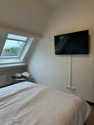 a bedroom with a bed with a flat screen tv on the wall at Catwijck Loft in Katwijk aan Zee