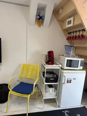 a yellow chair and a microwave and a refrigerator at Zomerhuisje Maranatha in Noordwijk aan Zee