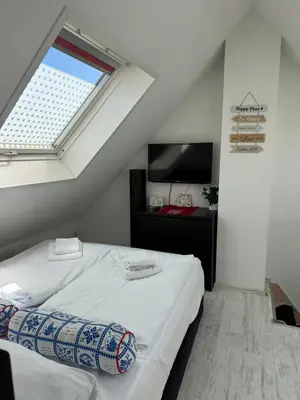 a bedroom with a white bed with a window at Zomerhuisje Maranatha in Noordwijk aan Zee