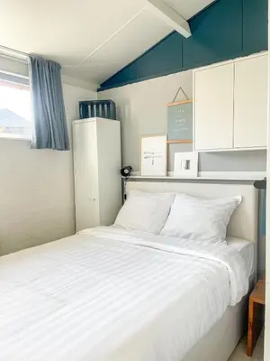 a bedroom with a white bed and a refrigerator at The Kingfisher near beach and dunes Hargen and Schoorl in Dirkshorn