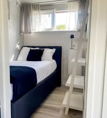 a bedroom with a bed with a ladder next to a window at The Kingfisher near beach and dunes Hargen and Schoorl in Dirkshorn