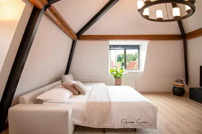 a bedroom with a white bed in a room with a window at ApartHotel De Koning by Urban Home Stay in Alkmaar