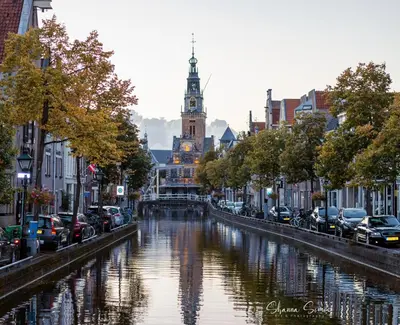 a river in a city with a clock tower at ApartHotel De Koning by Urban Home Stay in Alkmaar