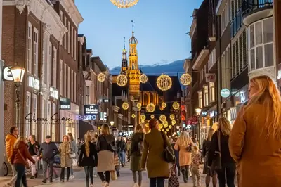 a crowd of people walking down a street with christmas lights at ApartHotel De Koning by Urban Home Stay in Alkmaar