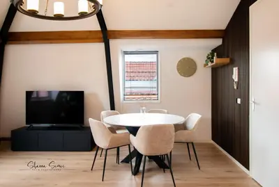 a dining room with a table and chairs and a tv at ApartHotel De Koning by Urban Home Stay in Alkmaar