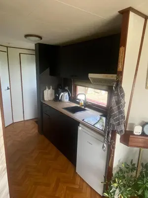 a small kitchen with black cabinets and a sink at Geniet van de rust en de ruimte in Bodegraven