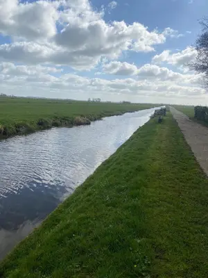 a river with benches on the side of it at Geniet van de rust en de ruimte in Bodegraven
