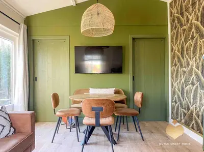 a dining room with green walls and a table and chairs at The Soultree - Stylish nature cottage near Schoorl dunes & Bergen beach in Warmenhuizen