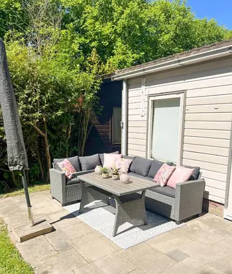 a patio with a couch and a table with pink pillows at The Soultree - Stylish nature cottage near Schoorl dunes & Bergen beach in Warmenhuizen