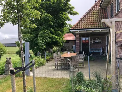 a patio with a table and chairs in front of a house at kleinrosenbrand in Burgerbrug