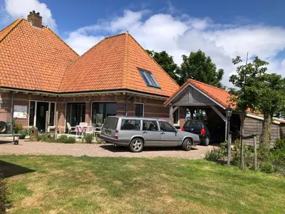 a car parked in front of a house with an orange roof at kleinrosenbrand in Burgerbrug