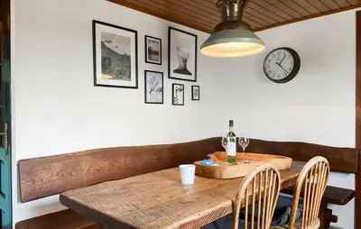 a dining room with a wooden table and a clock at Woonboot De Karekiet in Loosdrecht