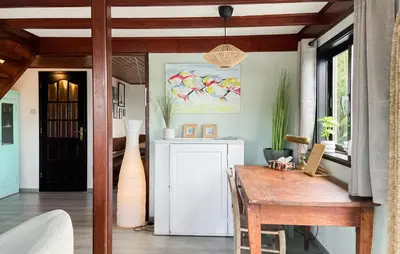 a dining room with a table and a painting on the wall at Woonboot De Karekiet in Loosdrecht