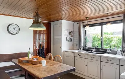 a kitchen with a table and a clock on the wall at Woonboot De Karekiet in Loosdrecht