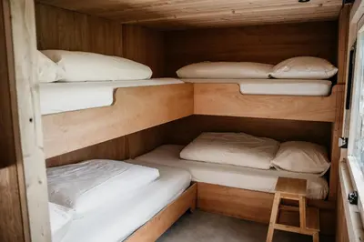 a room with three bunk beds and a stool at SRV wagen De Geus in Oud-Ade