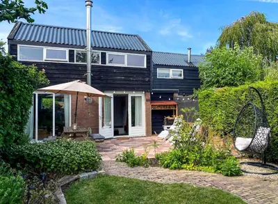 a black house with an umbrella in a yard at The Highlander- Stylish Hideaway near Beach & Forest Schoorl and Bergen- Dogs Welcome in Warmenhuizen