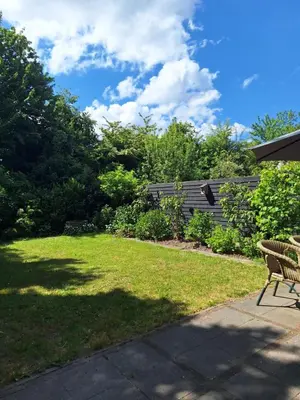 a patio with a lawn with a chair and trees at Rekerlanden 32 in Schoorldam
