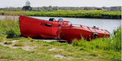 a red boat sitting on the side of a river at Rekerlanden 32 in Schoorldam