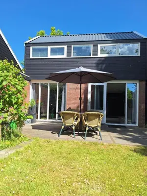 two chairs and an umbrella in front of a house at Rekerlanden 32 in Schoorldam