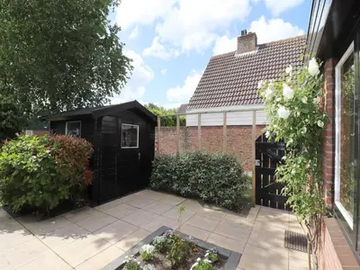 a black shed in the backyard of a house at Holiday Home in Noordwijkerhout by Forest & Lake in Noordwijkerhout