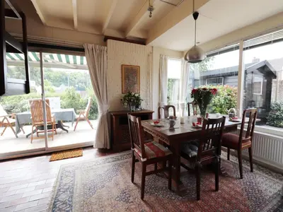 a dining room with a table and chairs and windows at Holiday Home in Noordwijkerhout by Forest & Lake in Noordwijkerhout