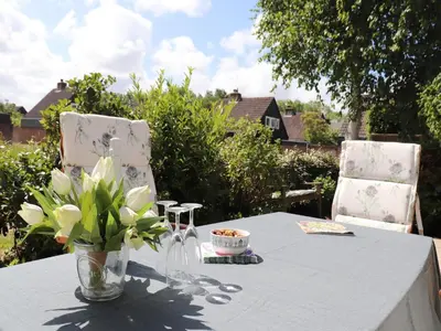 a table with a vase of flowers and two chairs at Holiday Home in Noordwijkerhout by Forest & Lake in Noordwijkerhout